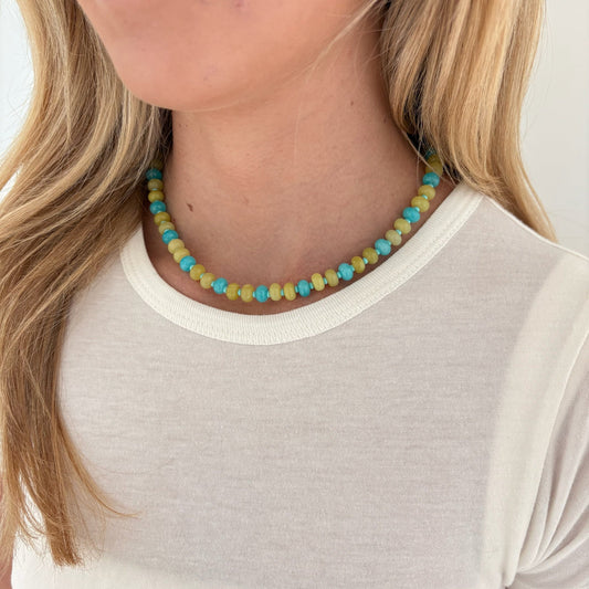 Necklace with small beads worn by a person against a neutral background