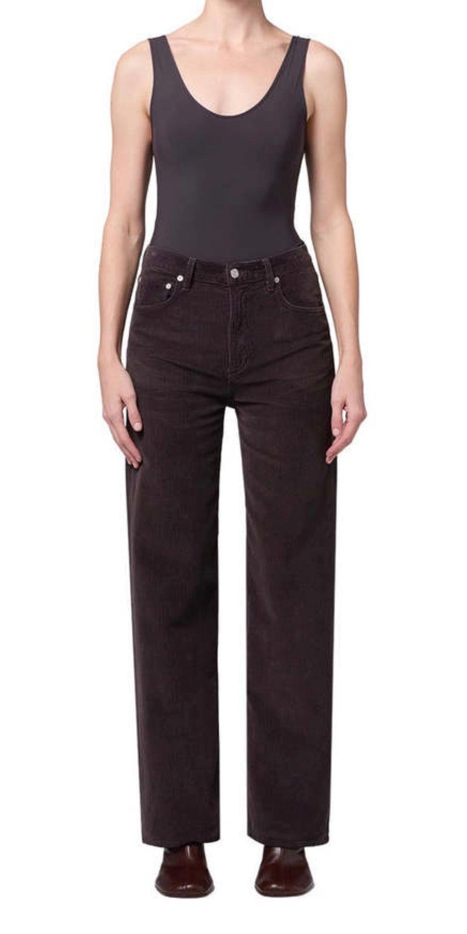 A model wearing a dark charcoal gray sleeveless bodysuit and dark brown wide-leg corduroy pants, paired with dark brown leather shoes, against a plain white background.