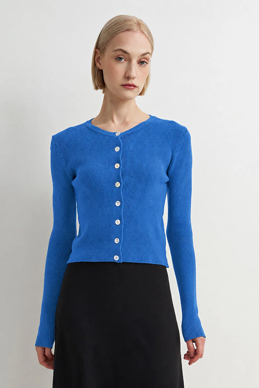 Woman wearing a blue cardigan with a plain background