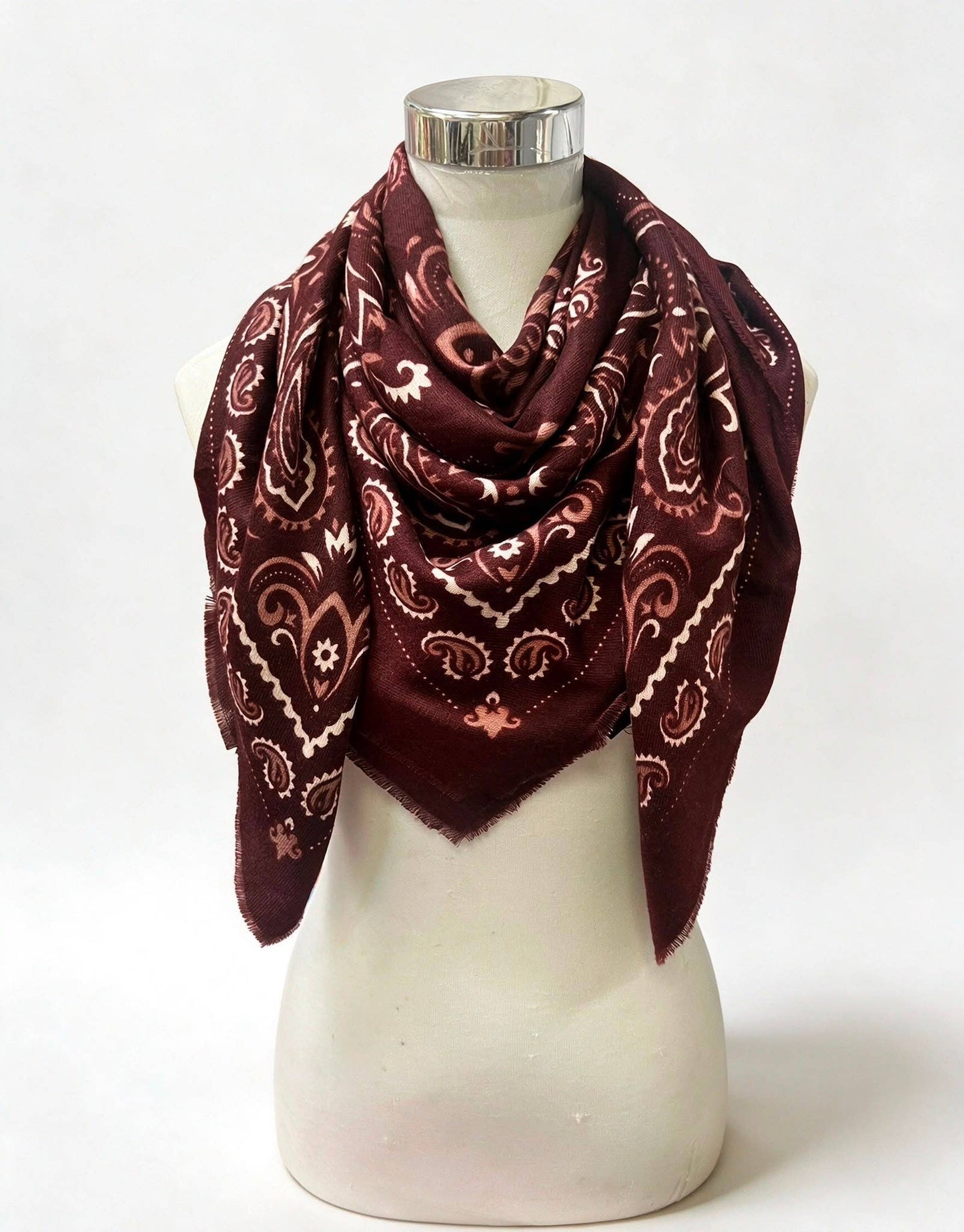 A dark burgundy bandana scarf with a cream paisley pattern, draped on a white mannequin torso against a white background.
