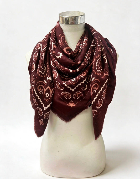 A dark burgundy bandana scarf with a cream paisley pattern, draped on a white mannequin torso against a white background.