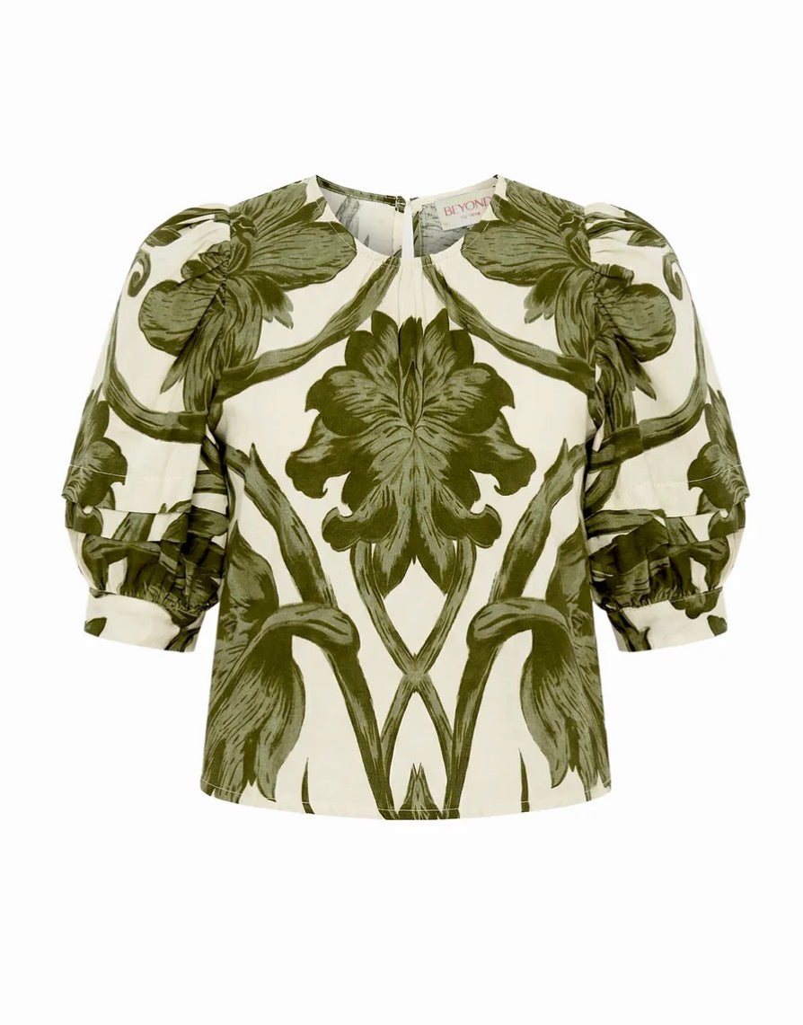 A women's blouse with a symmetrical, mirrored floral print in olive green on an off-white background, featuring puffed 3/4 sleeves and a round neckline.