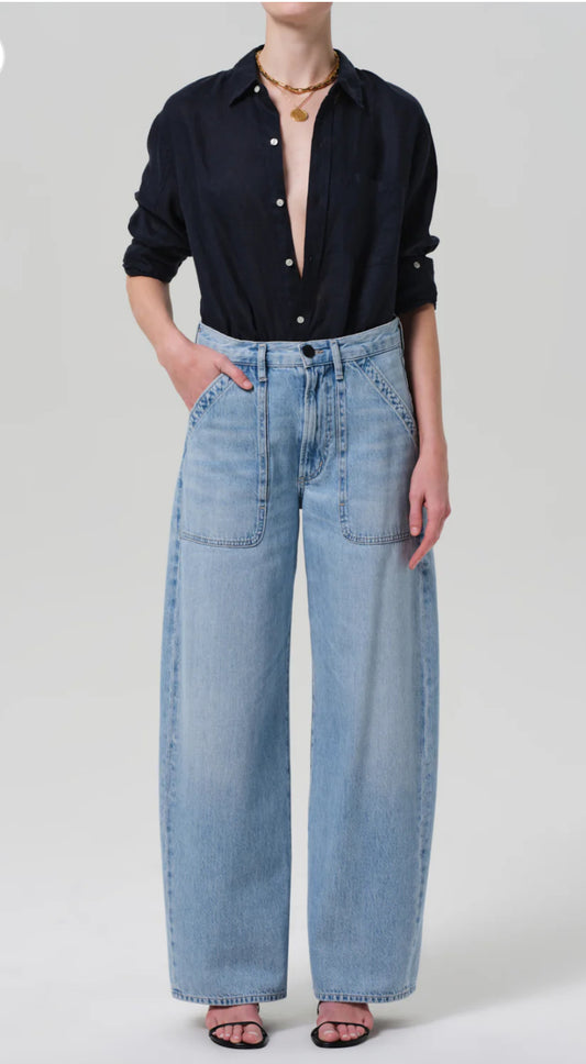 Person wearing a black button-up shirt and light blue jeans on a white background