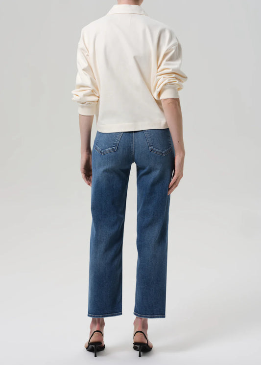 Person wearing a white sweater and blue jeans on a plain background