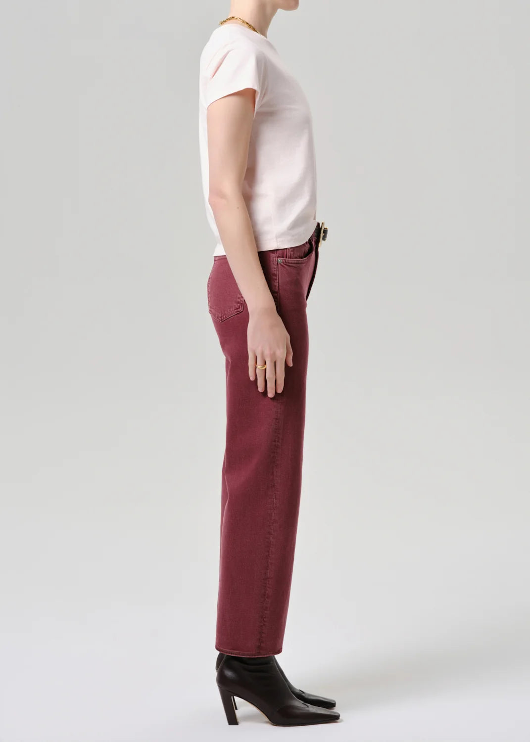 Person wearing a white top and maroon pants on a plain background
