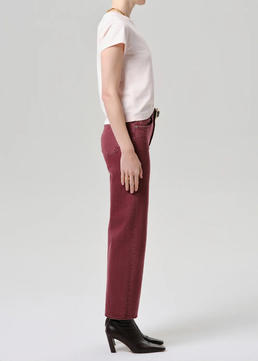 Person wearing a white top and maroon pants on a plain background