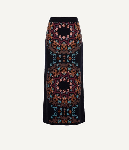 A black midi skirt featuring a symmetrical, ornate floral and scroll pattern in rust orange, teal blue, and burgundy, presented on a light gray background.