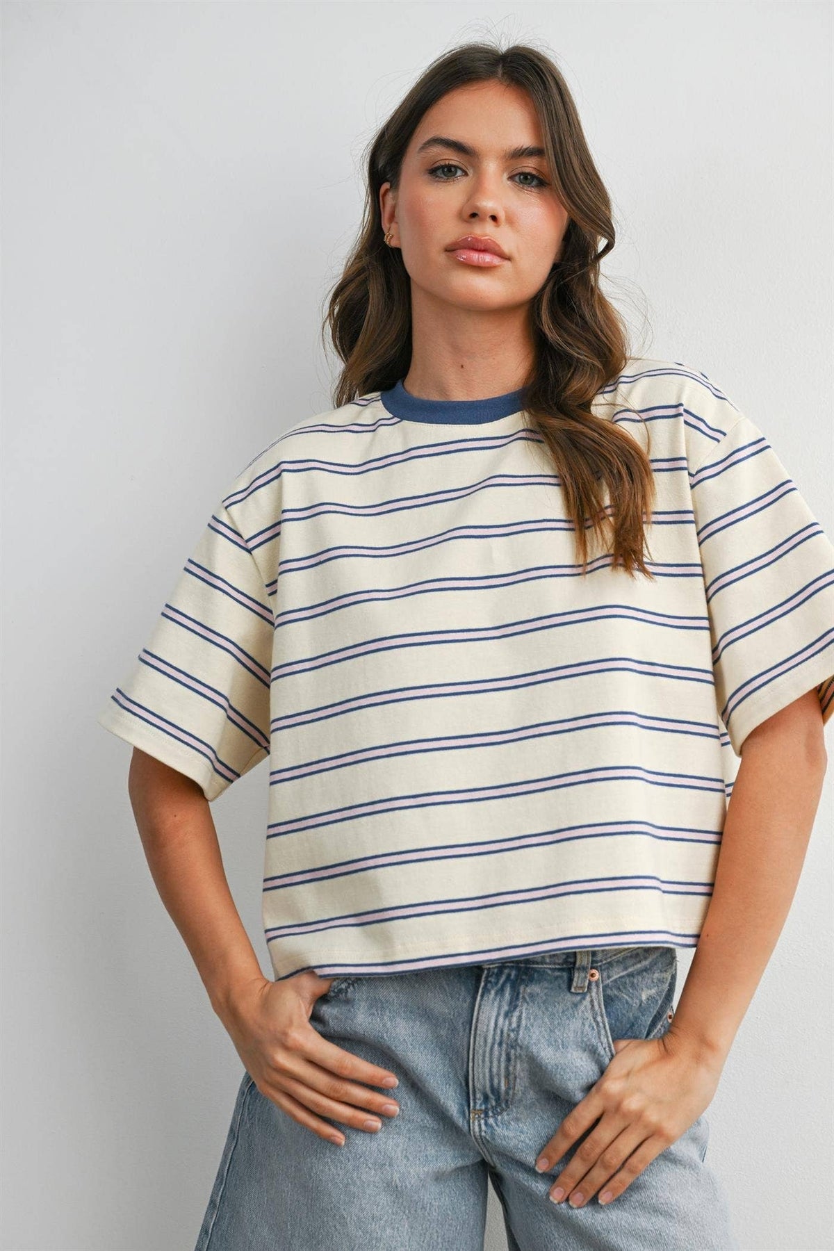 Woman wearing a striped shirt and jeans against a plain background