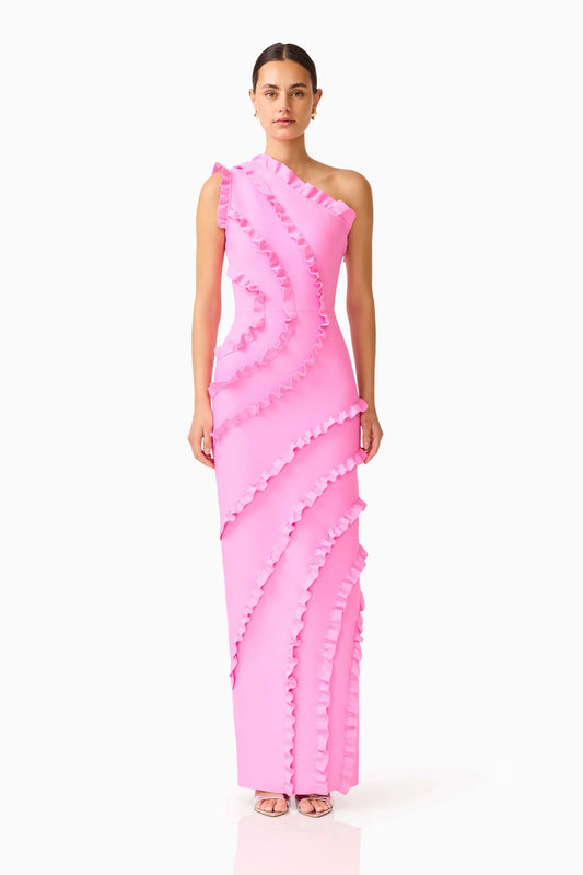 A model wearing a bright pink one-shoulder maxi dress with dramatic ruffle detailing, photographed against a seamless white studio background.