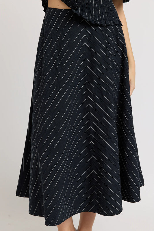 A black midi skirt with a white chevron stripe pattern, shown on a model against a light gray background.