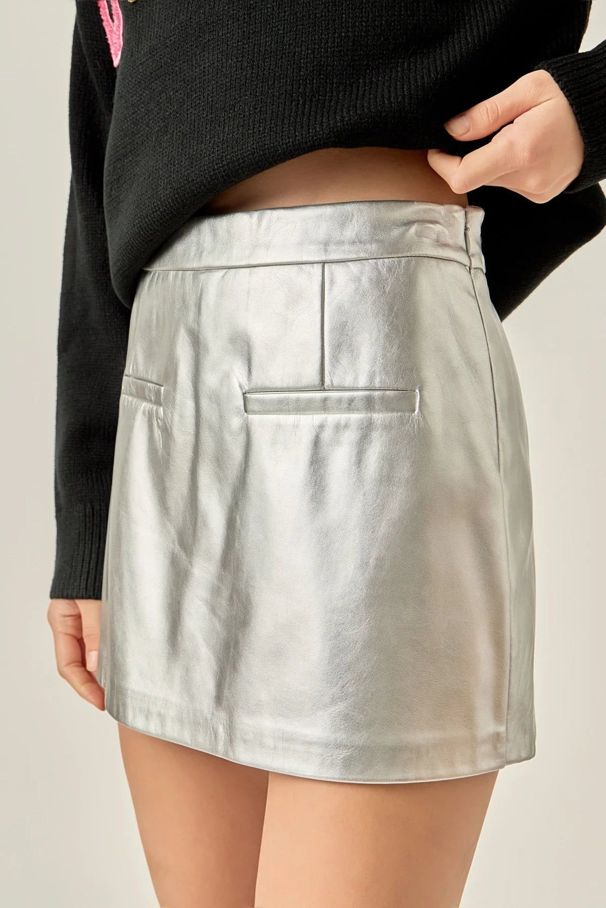 Silver skirt worn by a person on a plain background