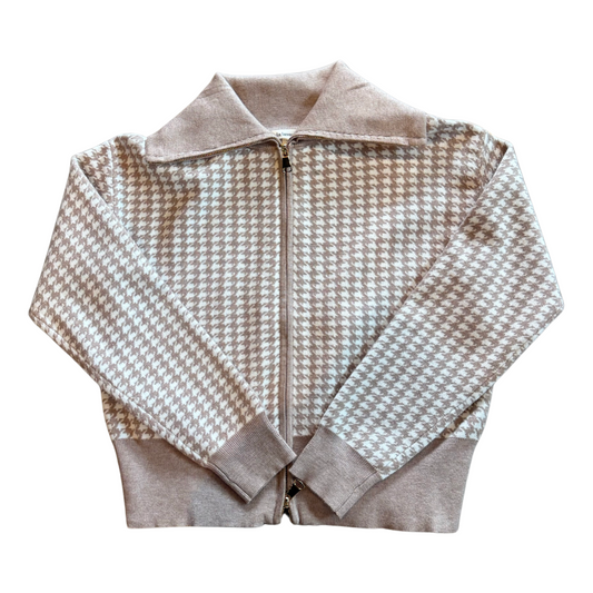 A  zip-up jacket featuring a beige and white houndstooth pattern, with solid beige ribbed trim on the collar, cuffs, and hem.