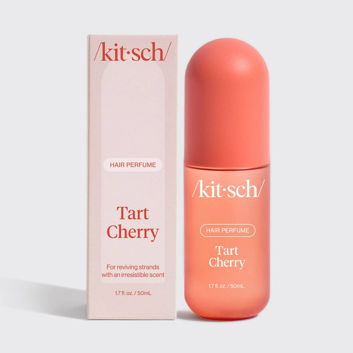 Kit-sch Tart Cherry hair perfume bottle in a peachy pink color next to its matching pink packaging box, on a light gray background.