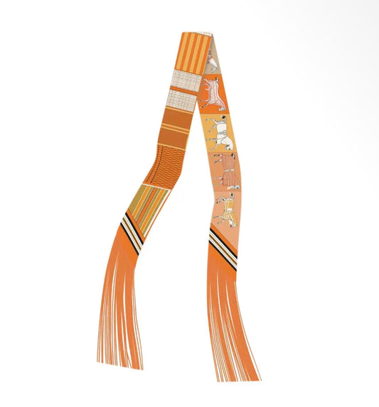 An orange and beige patterned scarf with fringe tassels, featuring stylized dog illustrations and geometric stripes, displayed on a clean white background.