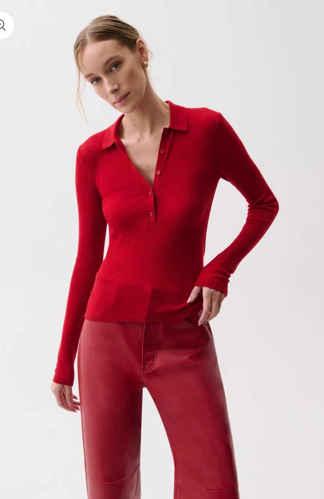 A woman modeling a fitted long-sleeve knit polo-style top in deep red, paired with matching red pants, against a clean light gray studio background.