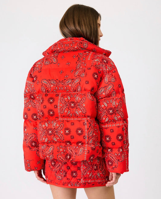 A model shown from the back wearing a red puffer jacket with a white and black paisley bandana print, set against a plain white studio background.