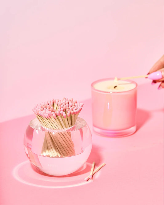 Pink candle and matchbox on a pink background