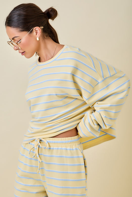 Woman wearing a yellow and blue striped outfit against a beige background